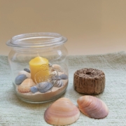 Weckglas mit Sand, Muscheln und Kerze dekoriert