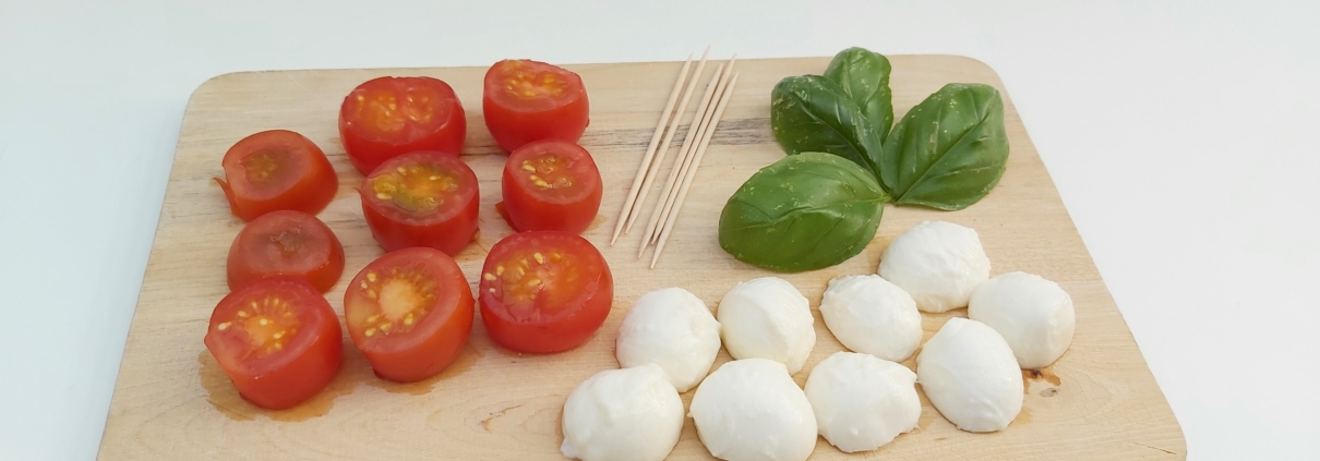 Brett mit Tomaten, Mozarella, Basilikum und Schaschlikspießen