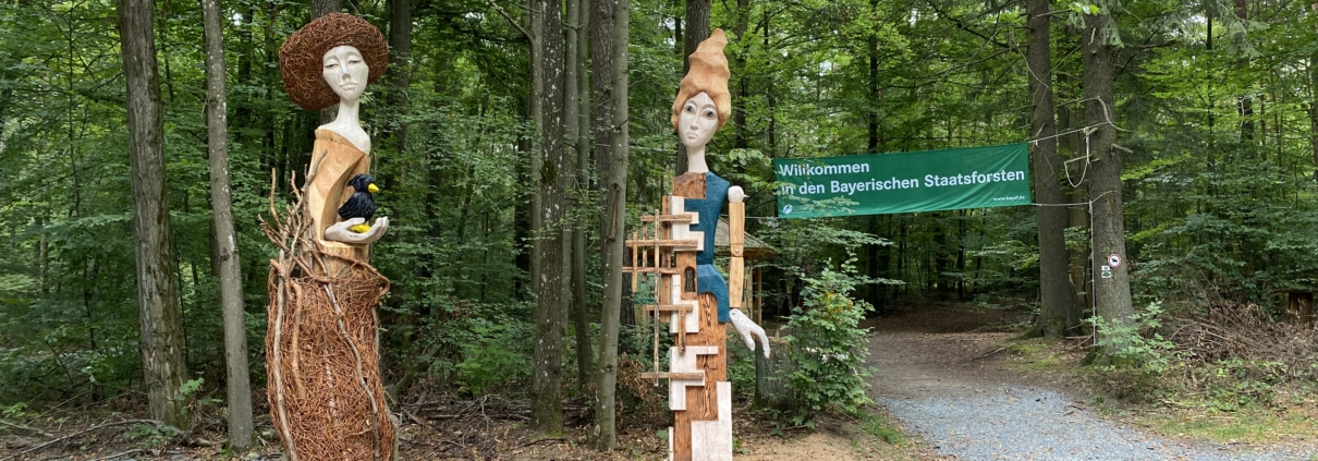 zwei Figuren aus Holz im Wald