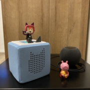 eine Lautsprecherbox mit einer Figur, ein singendes Maedchen obendrauf, daneben eine Figur, ein rosa Schweinchen
