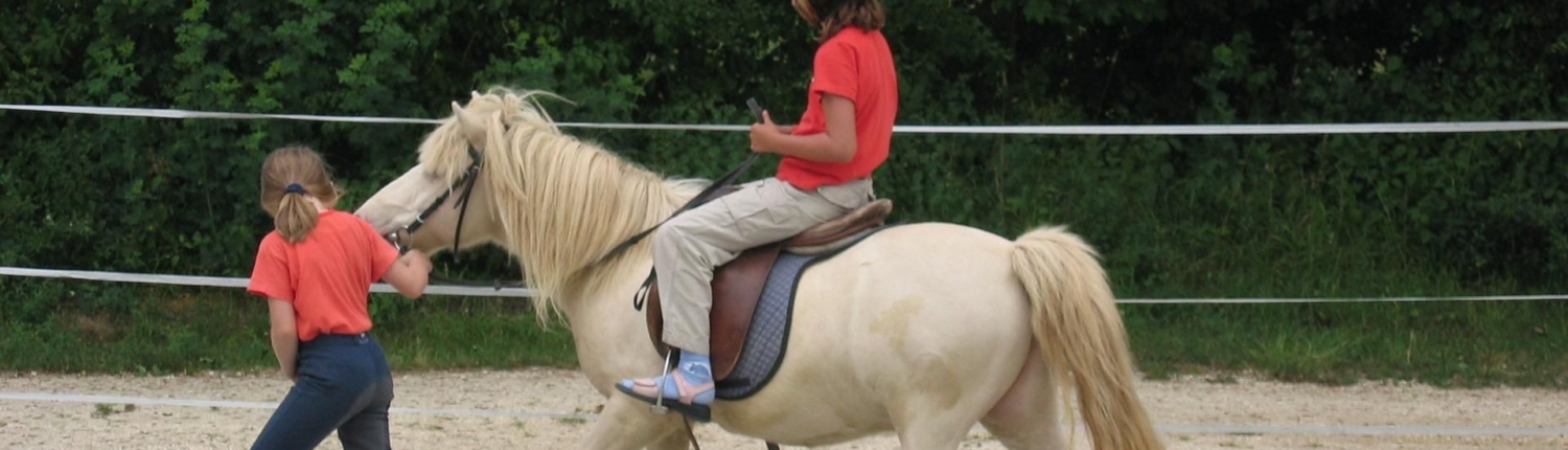 Kind reitet auf einem Pony, ein anderes Kind führt