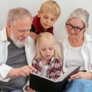 Großeltern mit Enkel und Enkelin, die ein Album anschauen